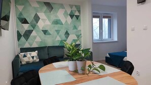 Una sala de reuniones moderna con una pared de estampado geométrico, una mesa redonda de madera y un sofá azul.