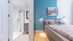 Ein modernes Schlafzimmer mit Bett, Dusche und einer blauen Akzentwand.