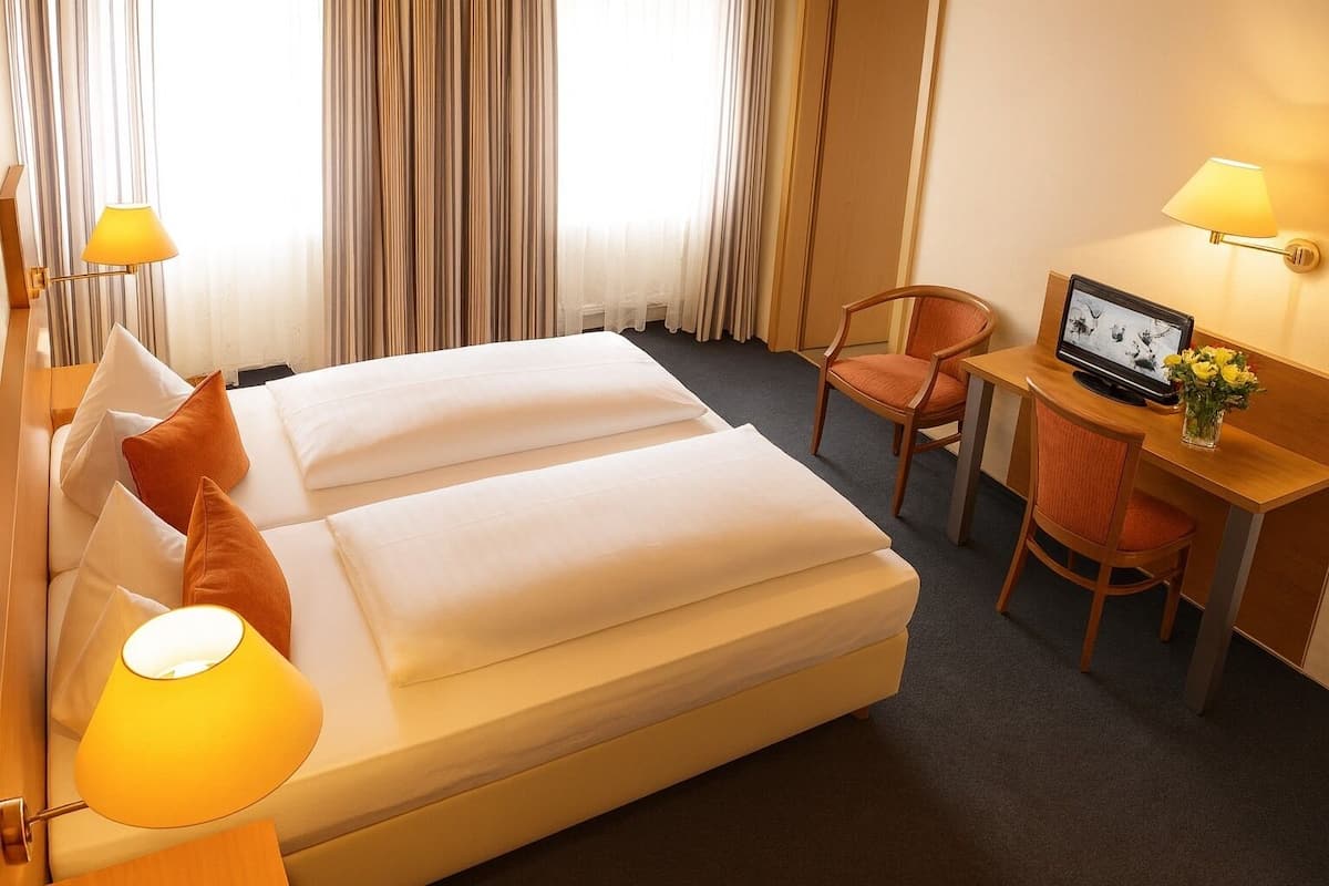 Hotellihuone, jossa on sänky, työpöytä, tuoli ja televisio.