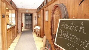 A wooden interior hallway with a chalkboard sign reading "Herzlich Willkommen" (Welcome). - Hotel-Restaurant Zum Kirschbaum (Rottendorf)