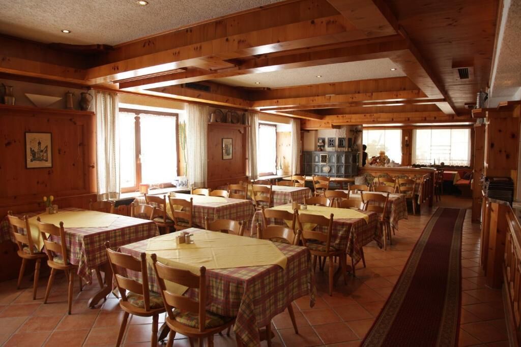 Un comedor amplio con varias mesas y sillas, paneles de madera y grandes ventanales que dejan entrar luz natural.