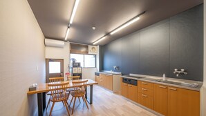 Een moderne keuken met houten kastjes, een eethoek met een tafel en stoelen, en een raam dat voor natuurlijk licht zorgt.