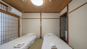 Een traditionele Japanse kamer met twee bedden, een houten plafond en een schuifdeur.