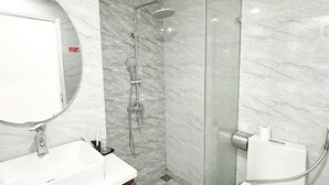 A modern bathroom with a marble floor, a white sink, a mirror, a glass shower enclosure, and a toilet. - Green Hotel Apartment HN- by Bay Luxury (Hanoi)