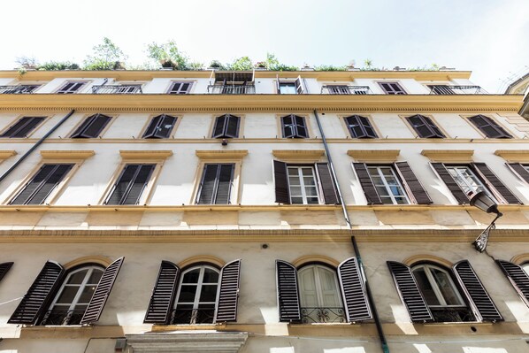 A multi-story building with arched windows and shutters, featuring a consistent architectural style. - Louly Trevi Fountain (Rome)