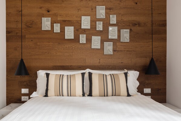 A bedroom with a wooden headboard, a bed with striped bedding, and multiple wall-mounted light fixtures. - Louly Trevi Fountain (Rome)