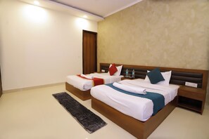 Una habitación de hotel con dos camas, un cabecero de madera, una mesita de noche y una alfombra.