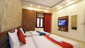 Une chambre d’hôtel avec deux lits, une télévision et une armoire.