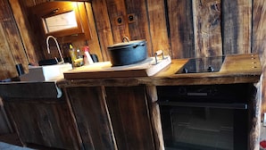 Una cocina rústica con encimera de madera, un fregadero, una estufa y un microondas.