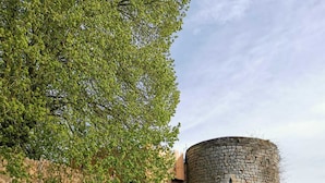 Una torre de piedra con una escalera de madera que sube hacia un edificio.
