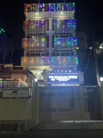 Un edificio de varios pisos con luces de cuerda de colores. El edificio tiene un cartel que dice 'The Sparkling Turtle Backpackers Hostel Pvt. Ltd.'