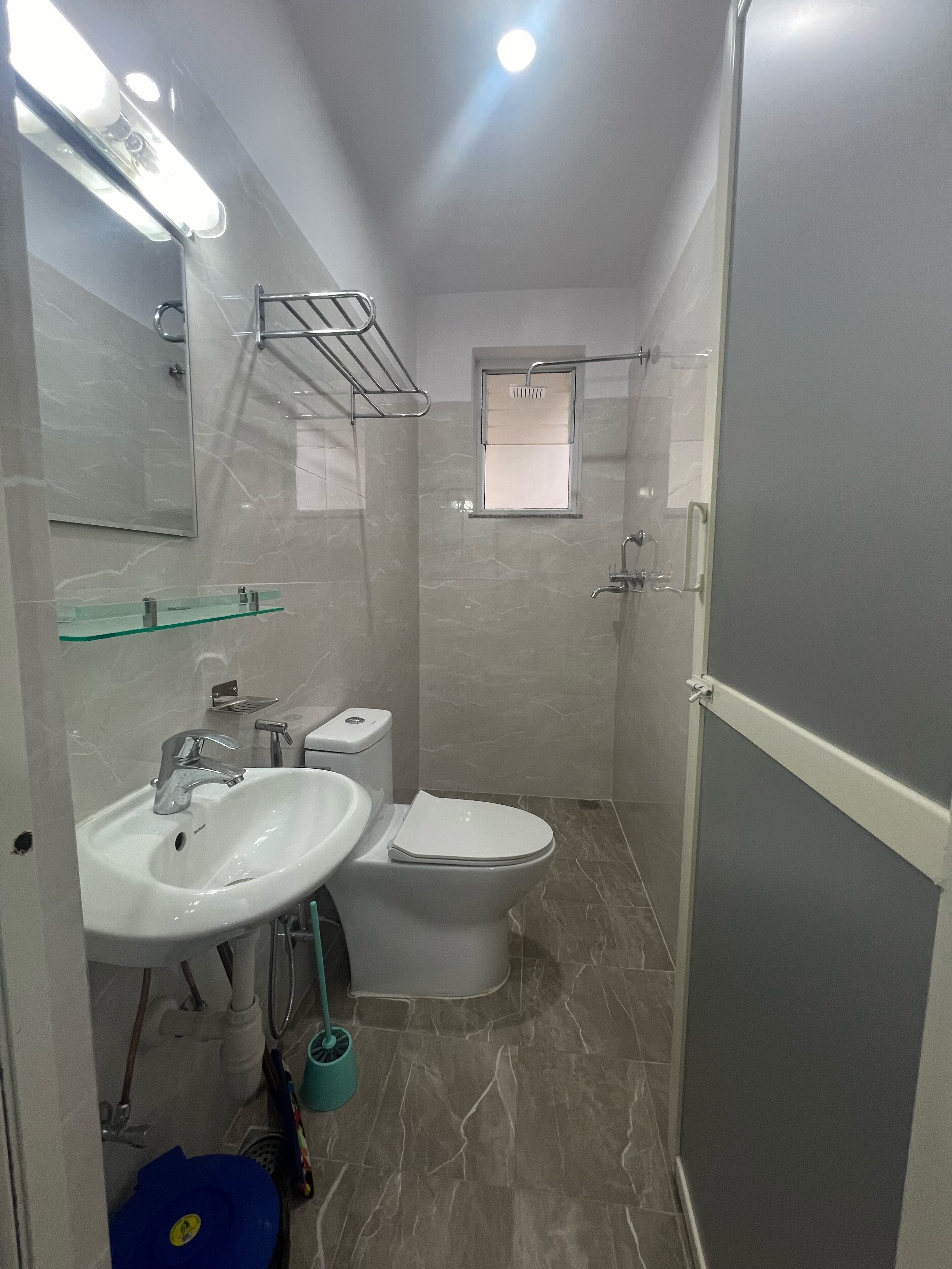 A compact bathroom with a white sink, toilet, and a glass shower enclosure.