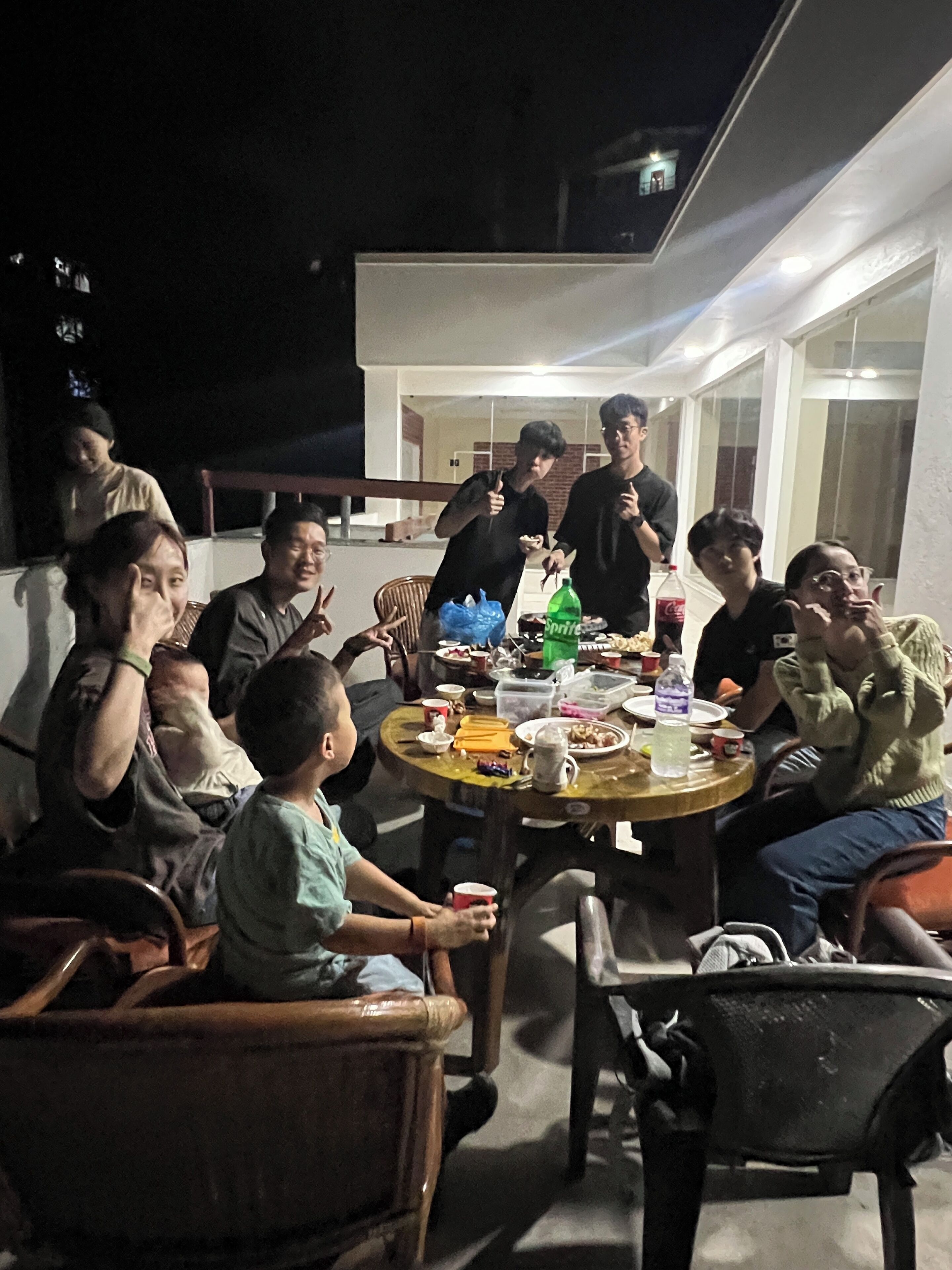 A group of people seated around a round table outdoors at night.
