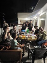 Un grupo de personas sentadas alrededor de una mesa redonda al aire libre por la noche.