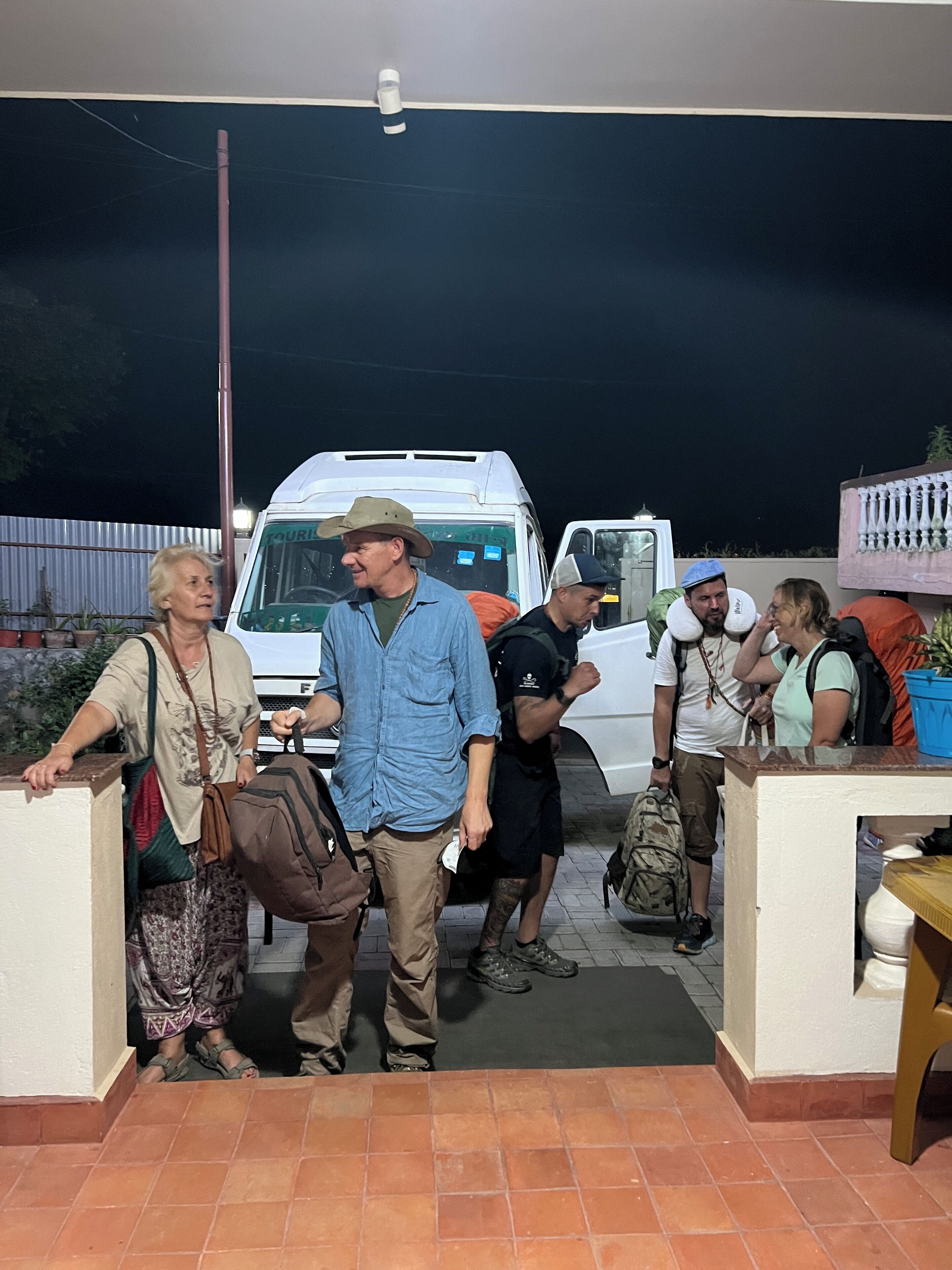 A group of people boarding a white van at night.