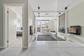 A modern living room with a fireplace, a dining area, and a view of the outside. - RentPlanet - Apartament na Śródmieściu (Warsaw)