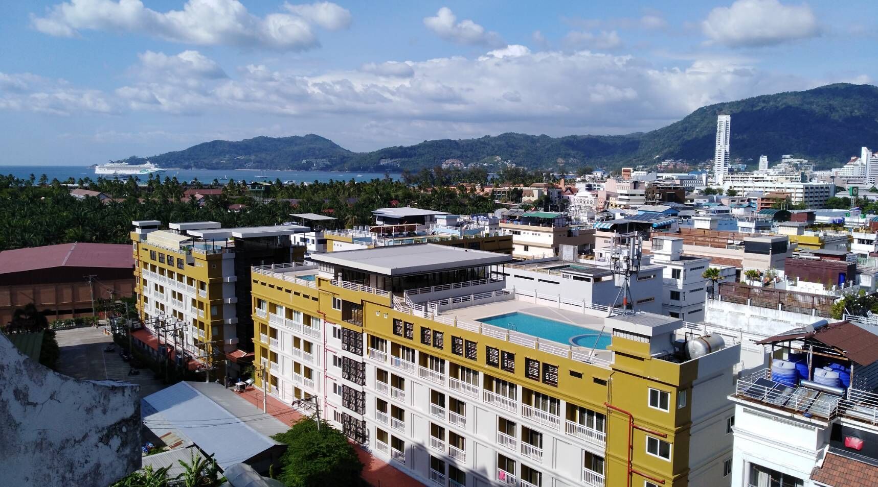 A high-rise hotel with multiple floors, balconies, and a rooftop pool.