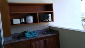 A compact kitchen with a sink, a rice cooker, and a microwave on a shelf. - Spacieux Studio, Tres Belle vue mer sur la Baie de Patong (Tambon Patong)