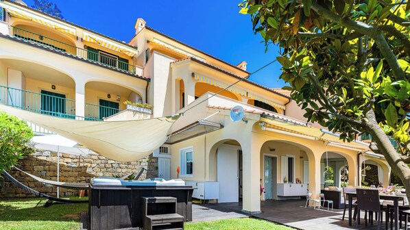 A two-story building with a patio area featuring outdoor furniture, a hot tub, and a dining setup. - House "The Seagull" with garden/ grill/ jacuzzi sea view (Bordighera)