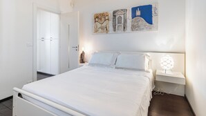 A bedroom with a bed, bedside table, and a wall-mounted artwork. - House "The Seagull" with garden/ grill/ jacuzzi sea view (Bordighera)