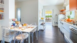 A modern kitchen with white cabinets, a stainless steel range, and a dining area with a white table and clear chairs. - House "The Seagull" with garden/ grill/ jacuzzi sea view (Bordighera)