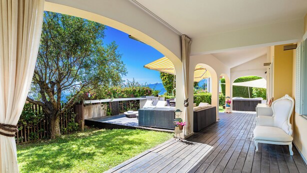 An outdoor patio with wooden flooring, seating arrangements, and a view of a tree and landscape. - House "The Seagull" with garden/ grill/ jacuzzi sea view (Bordighera)