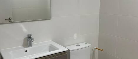 A modern bathroom with a white sink, vanity, and toilet.