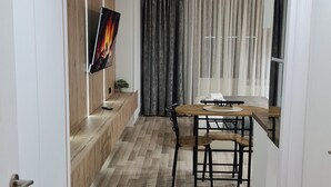 Una cocina moderna con encimera de madera, una mesa de comedor con sillas y un televisor montado en la pared.