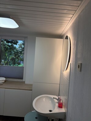 A bathroom with a white sink, a mirror, and a window with blinds.