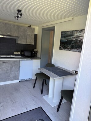 A compact kitchen with a microwave, stove, and cabinets. There is a dining area with a table and two chairs.