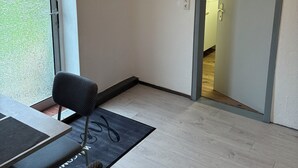 Huone, jossa on ruokailutila, kattovalaisin, seinälle kiinnitetty koriste ja ovi, joka johtaa toiseen huoneeseen.