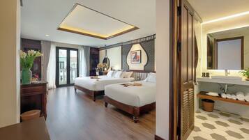 A hotel room with two beds, a wooden desk, a mirror, and a bathroom with a sink and towel rack.