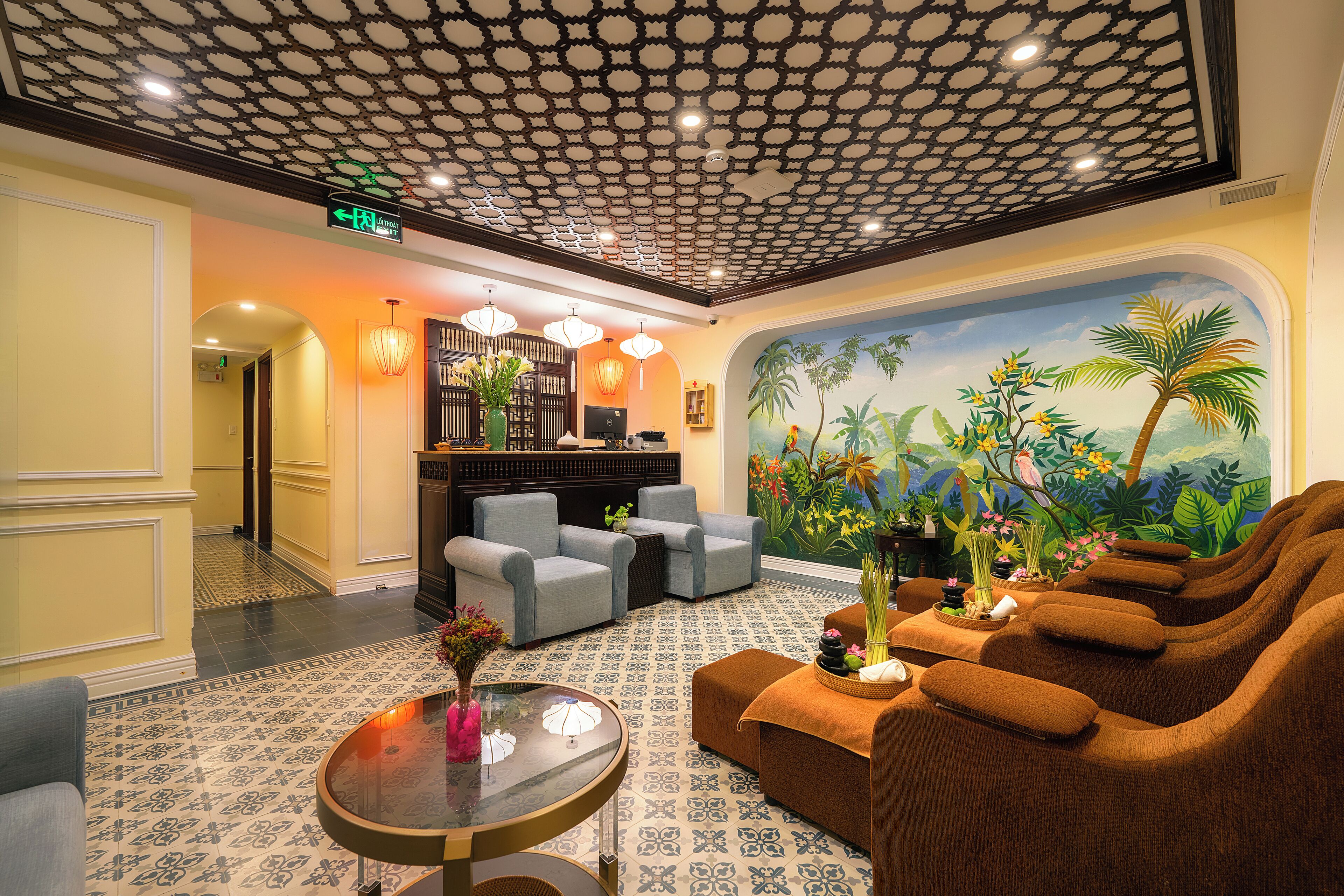 A lobby with a patterned floor, a reception desk, seating area, and a mural of a tropical scene.