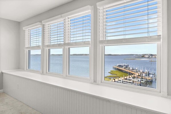 A room with a large bay window overlooking a marina with boats and docks.