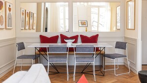 A dining area with a white table and four grey chairs, red cushions, and artwork on the walls. - Avignon Centre Historique/3chambres/ 2 Salles Bain/ Clim/ 200m Palais des Papes (Avignon)