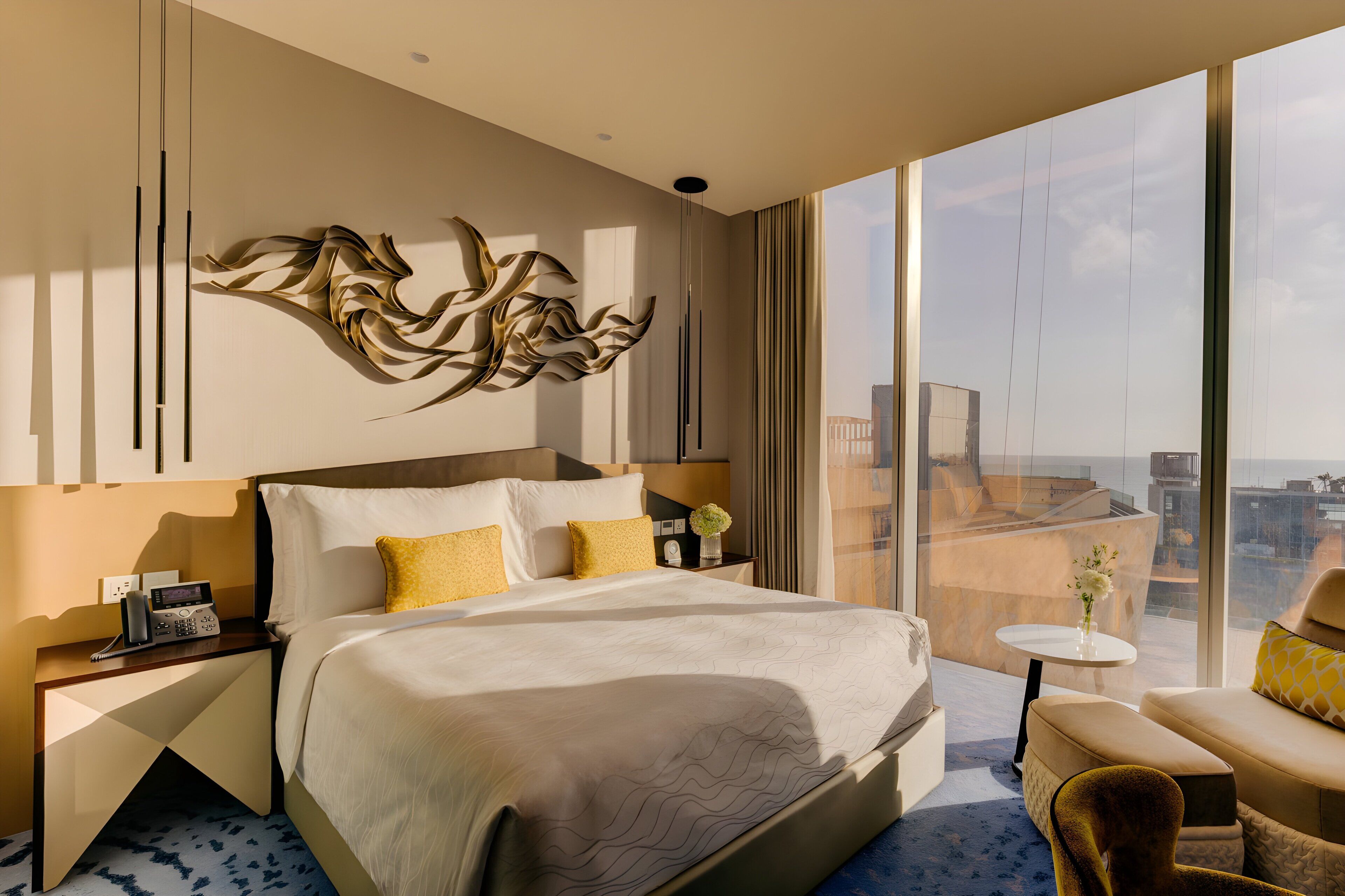 A modern hotel room with a large bed, a seating area, and a view of the cityscape.