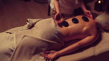 A massage therapy session with a person lying on a massage table, receiving treatment with heated stones.