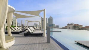 A rooftop pool area with lounge chairs and a city skyline in the background.