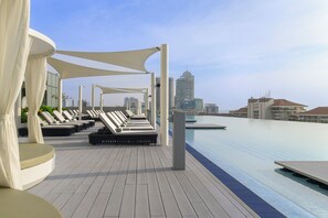 A rooftop pool area with lounge chairs and a city skyline in the background.