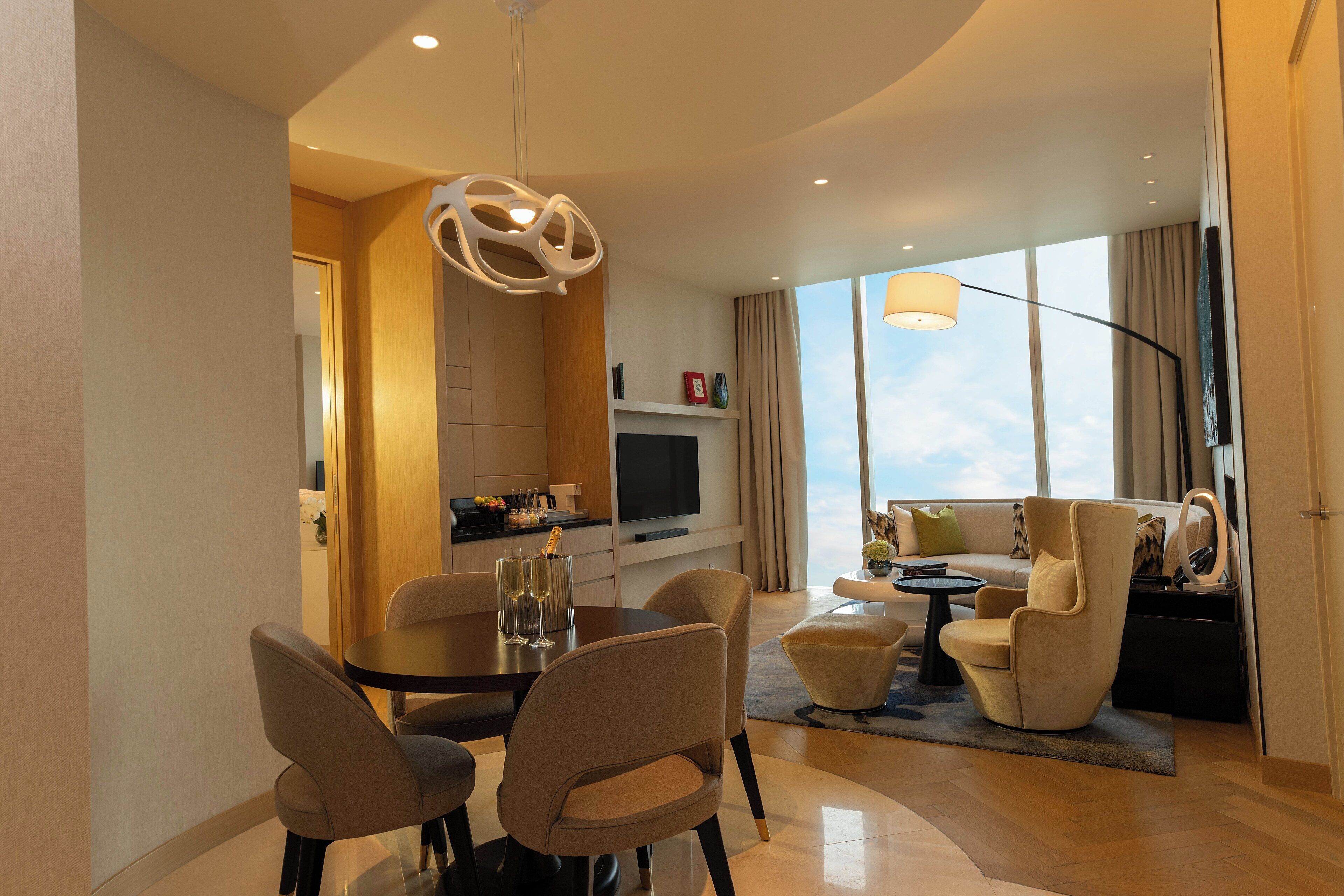 Ein modernes Wohnzimmer mit Essbereich, einem Flachbildfernseher und einem großen Fenster mit Blick auf den Himmel.