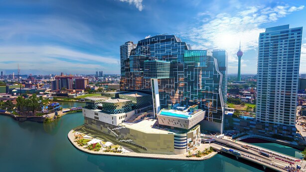 Un hotel moderno con un diseño arquitectónico único, ubicado frente al agua y conectado al edificio principal por un puente.