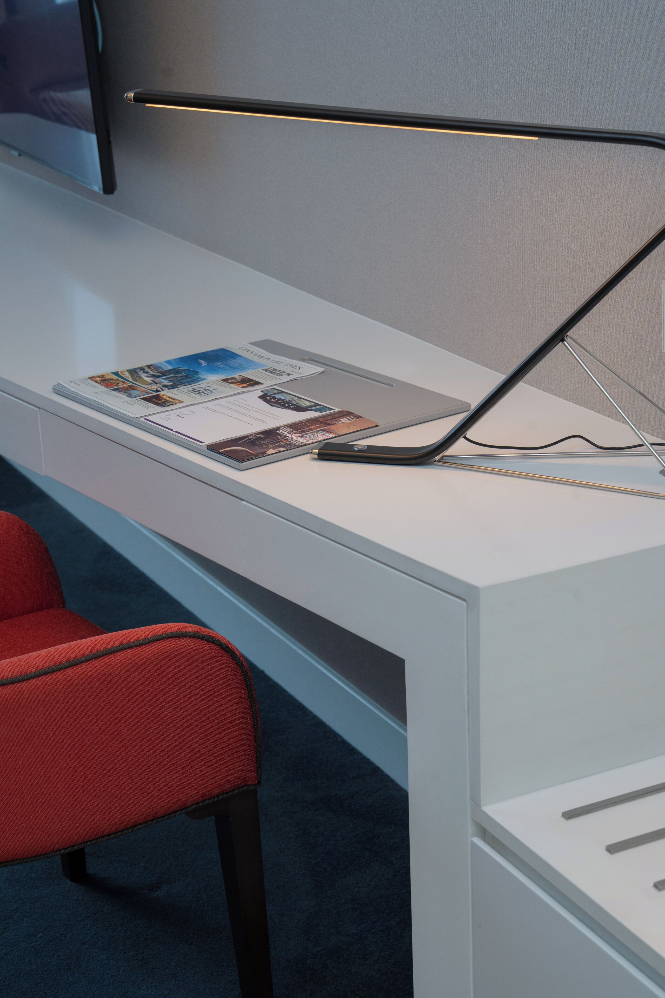 A modern office desk with a laptop, a magazine, and a pen.