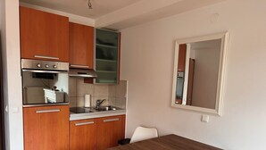 Eine kleine Küche mit Holzschränken, einem eingebauten Ofen und einem Essbereich mit Holztisch und weißen Stühlen.