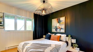 A modern bedroom with a large bed, a unique ceiling light, and a painting on the wall. - Waterfront, hot tub, dock, beautiful view (Wentworth-Nord)