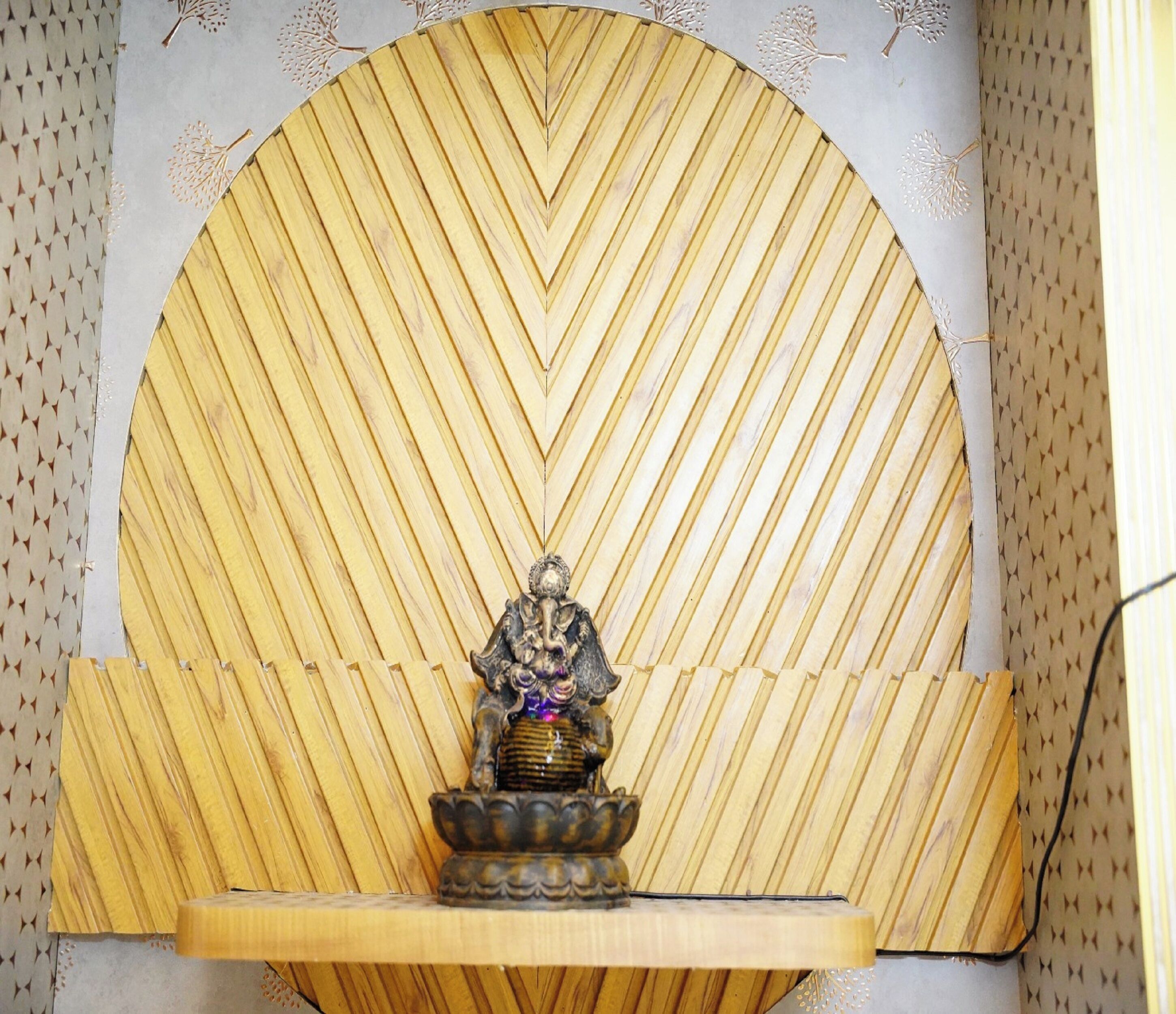 Une pièce avec un grand mur orné d’un motif en chevrons et une petite statue posée sur une étagère.