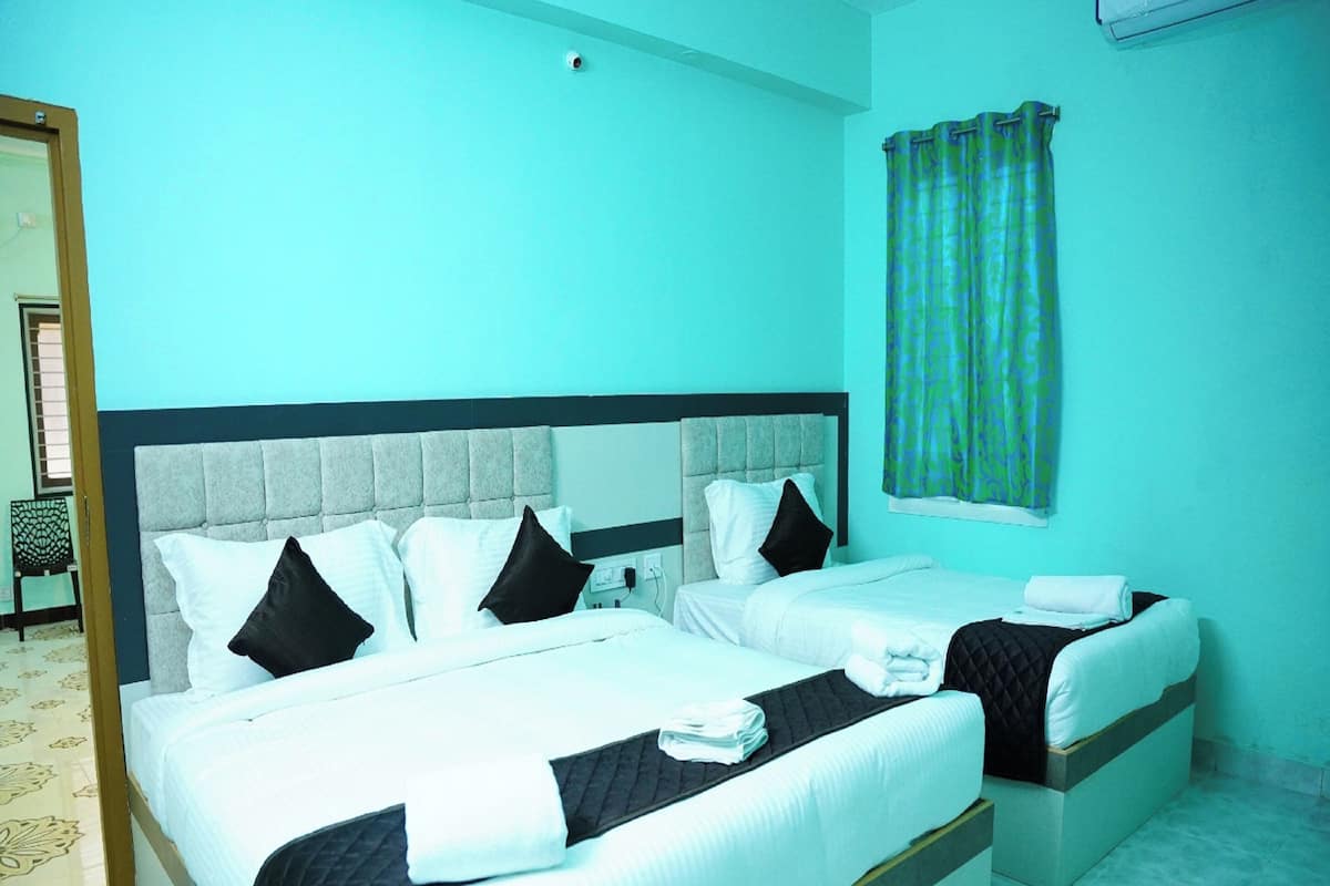 A hotel room with two beds, a large window with curtains, and a visible door.
