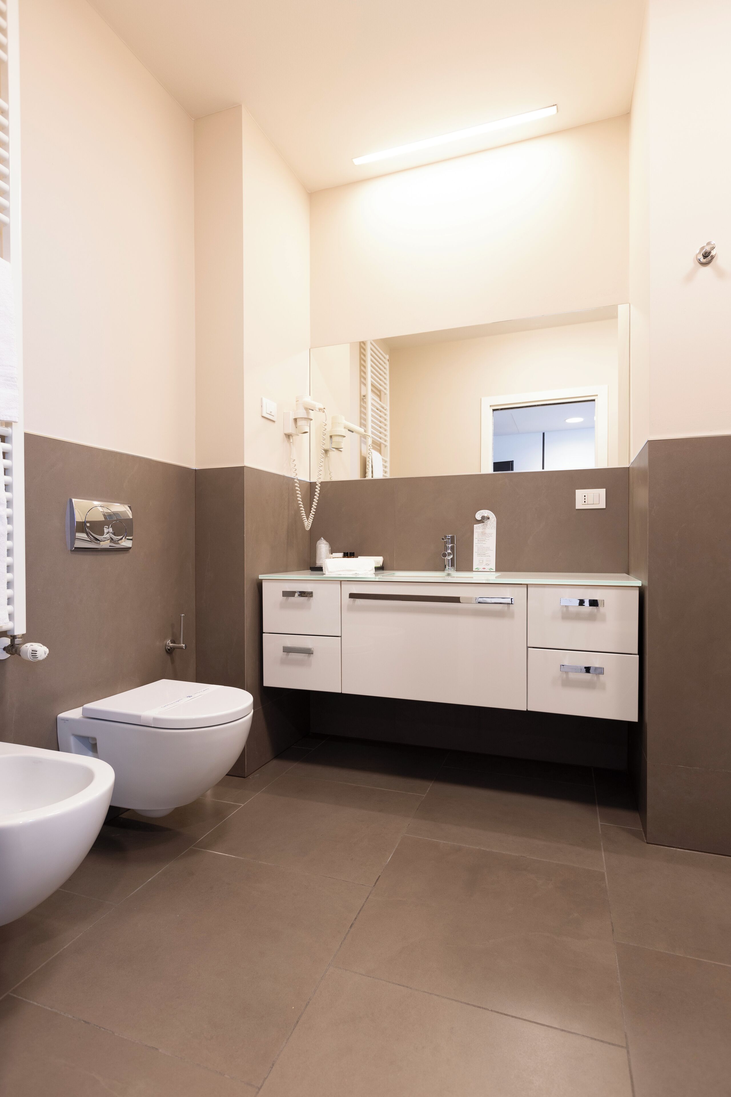 A modern bathroom with a toilet, bidet, and a vanity with a mirror.