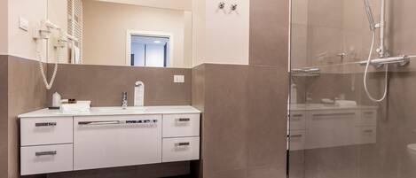 A modern bathroom with a glass shower enclosure, a white vanity with a mirror, and a toilet.