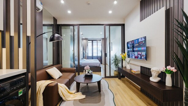 Une chambre d’hôtel moderne équipée d’un canapé, d’une table basse, d’une télévision, d’une armoire et d’un balcon avec un lit.