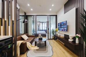 Une chambre d’hôtel moderne équipée d’un canapé, d’une table basse, d’une télévision, d’une armoire et d’un balcon avec un lit.